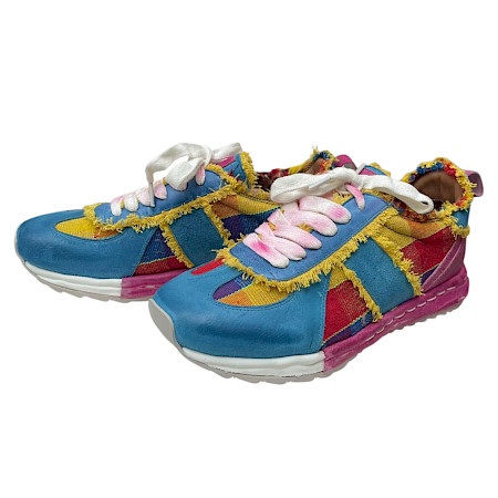 Bunter Sneaker mit auffälligem Patchwork-Design in Blau, Pink und Gelb, kombiniert mit Fransen-Details und weißen Schnürsenkeln. Bunter Sneaker mit auffälligem Patchwork-Design in Blau, Pink und Gelb, kombiniert mit Fransen-Details und weißen Schnürsenkeln.