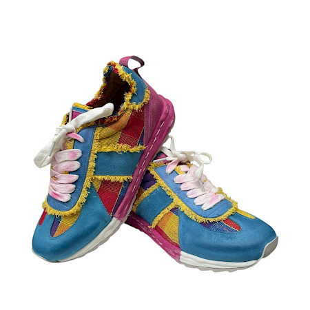 Bunter Sneaker mit auffälligem Patchwork-Design in Blau, Pink und Gelb, kombiniert mit Fransen-Details und weißen Schnürsenkeln. Bunter Sneaker mit auffälligem Patchwork-Design in Blau, Pink und Gelb, kombiniert mit Fransen-Details und weißen Schnürsenkeln.